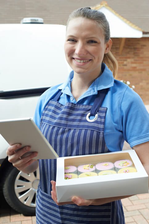 Female Baker With Digital Tablet Making Home Delivery Of Cupcakes