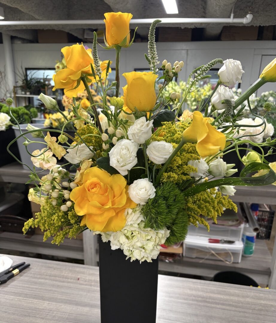 Yellow roses and white flowers in black vase