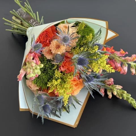 Colorful wrapped bouquet with thistles and roses