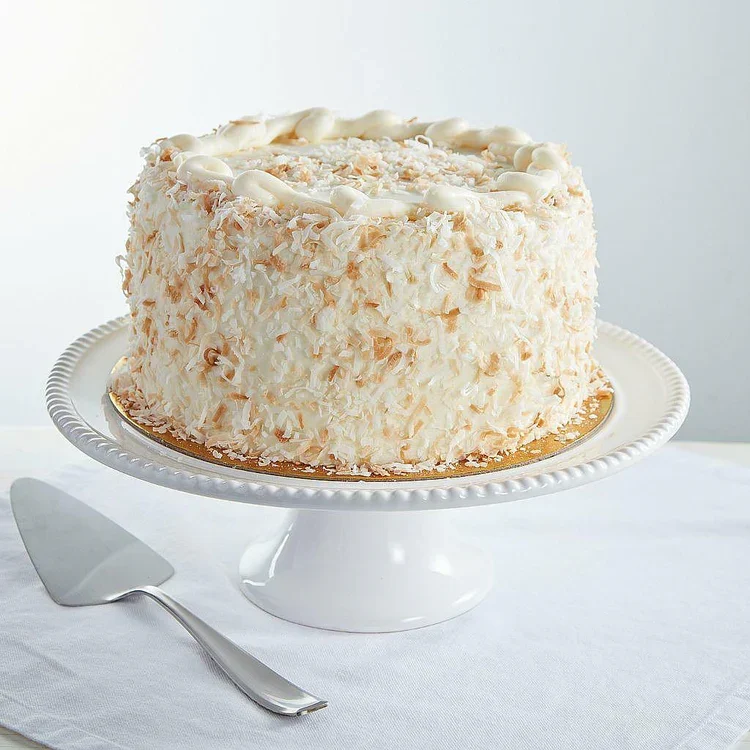 Coconut cake on white pedestal with server