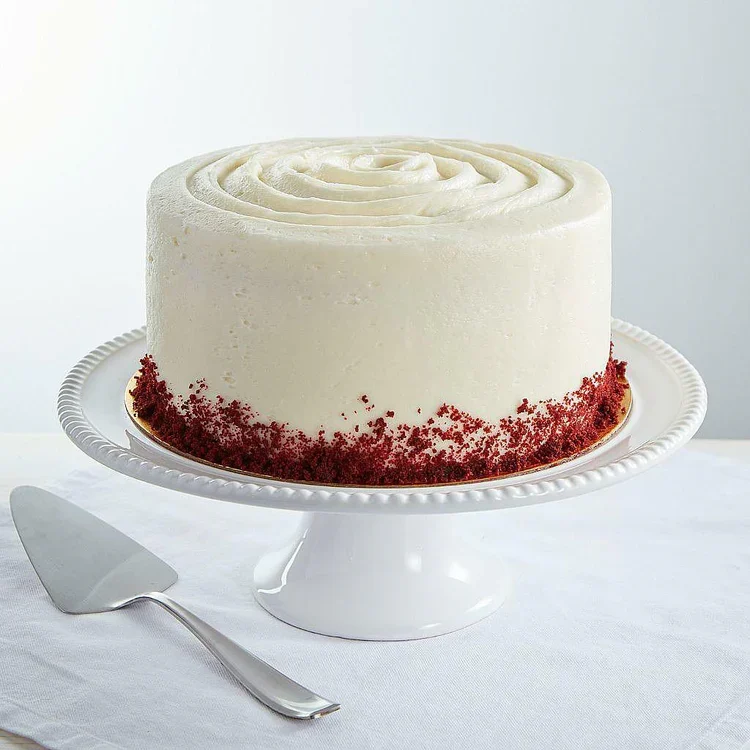 Frosted red velvet cake on stand