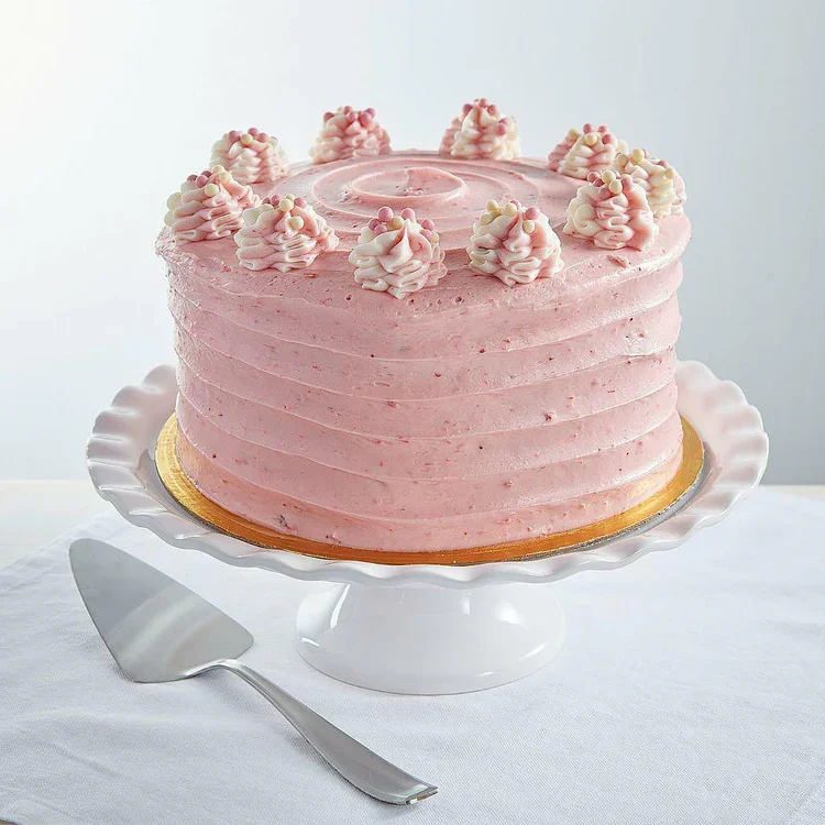 Pink frosted layer cake with piped swirls